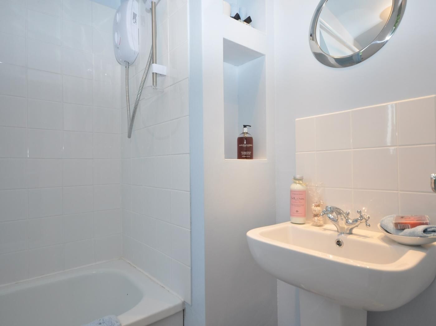 Un baño con bañera, lavamanos, espejo y ducha.