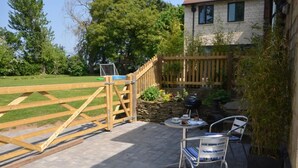 A patio with a wooden fence, a barbecue grill, and outdoor seating. - 1 Bed in Gloucester (oc-oldbn) (Upton Saint Leonards)
