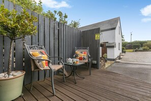 Ein Patio mit zwei Stühlen, einem Tisch und einem Blumentopf.