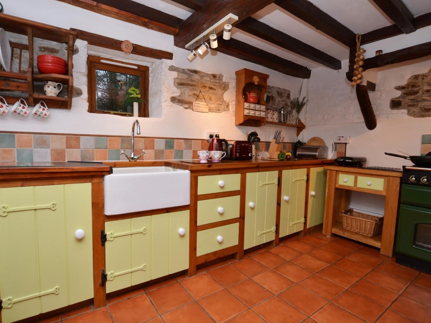 Une cuisine avec un mur recouvert de carreaux, des meubles en bois, un évier et une cuisinière.