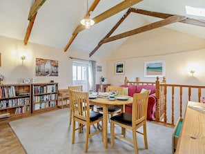 Ein gemütliches Zimmer mit Holztisch, Stühlen, einem Bücherregal und einem roten Sofa.