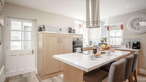 Una cocina moderna con armarios de madera, una isla central y un reloj de pared grande.