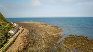 Zona costera con costa rocosa, una carretera que lleva a una hilera de edificios y vista al mar.