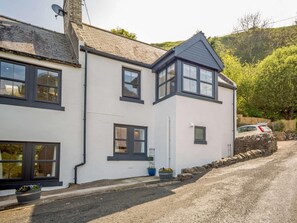 A two-story house with a white exterior and dark trim, a sloped roof, and a driveway leading to a parked car. - 3 Bed in Burnmouth (oc-78485) (Burnmouth)