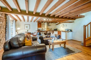 A cozy living room with leather sofas, a wooden coffee table, and a kitchen in the background. - 2 Bed in Penrith (oc-79466) (Kirkland)