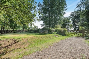 A grassy outdoor area with a gravel path leading to a wooden gate. - 2 Bed in Penrith (oc-79466) (Kirkland)