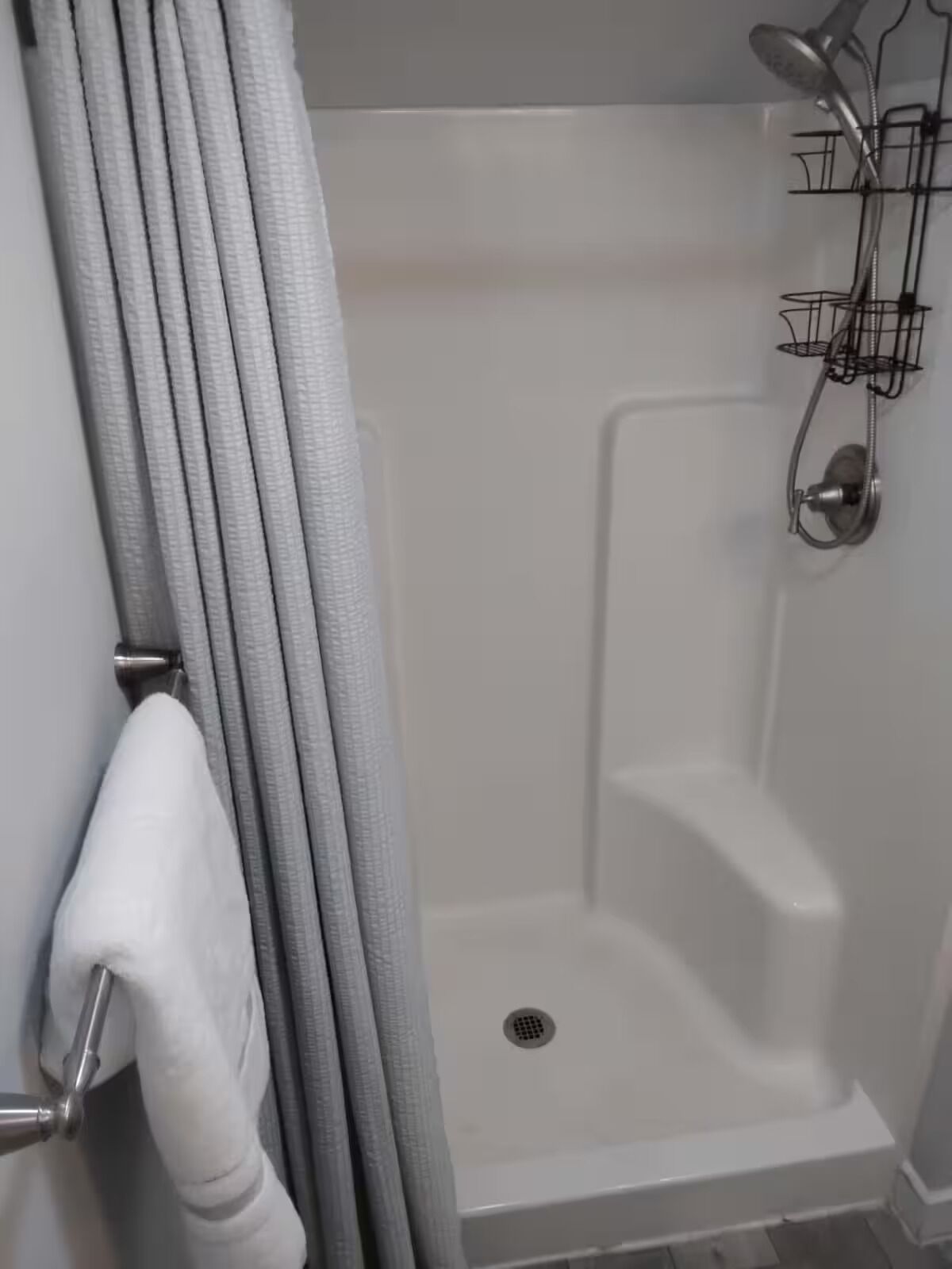 Une douche équipée d’un pommeau de douche à main, d’un porte-serviettes mural et d’un panneau de commande de la douche.