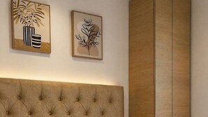 Ein Schlafzimmer mit einem karrierten Kopfteil, weißer Bettwäsche und zwei gerahmten Kunstwerken an der Wand.