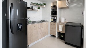 Eine moderne Küche mit einem schwarzen Kühlschrank, Holzschränken, einem eingebauten Backofen und einer Mikrowelle.