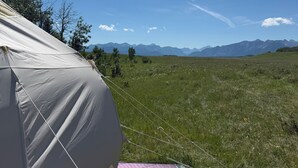 A tent set up in a grassy field with a clear sky and distant mountains. - High End Glamping Tent! Amazing Mountain Scenery! Kananaskis country! Privacy! (Calgary)