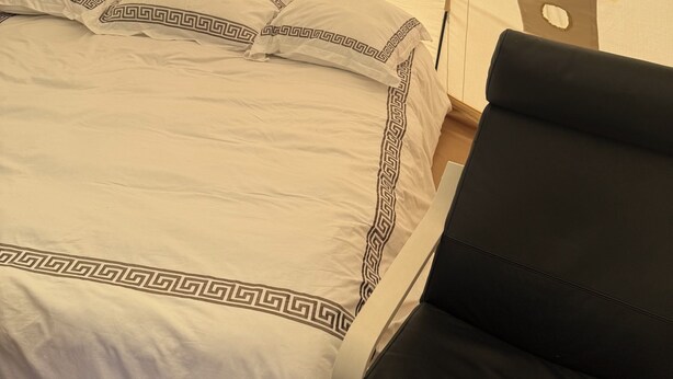A bed with a white and black patterned bedspread, a black chair, and a tent-like structure in the background. - High End Glamping Tent! Amazing Mountain Scenery! Kananaskis country! Privacy! (Calgary)