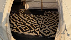 A tent with a bed inside, a patterned mat on the floor, and trees in the background. - High End Glamping Tent! Amazing Mountain Scenery! Kananaskis country! Privacy! (Calgary)