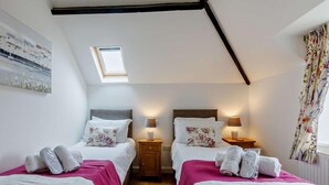 A bedroom with two beds, a skylight, wooden floors, and a painting on the wall. - 2 Bed in Bideford (oc-housm) (Higher Clovelly)