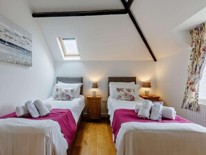 Ein Schlafzimmer mit zwei Betten, einem Oberlicht, Holzböden und einem Bild an der Wand.