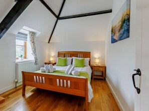 Ein Schlafzimmer mit einem hölzernen Bett, einem fenster mit Vorhängen, einem Heizkörper und einem Bild an der Wand.