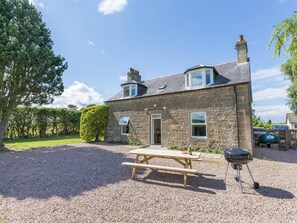A stone house with a gravel driveway, a picnic table, and a barbecue grill. - 3 Bed in Elgin (oc-ca294) (Elgin)