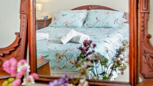 Quarto com colcha florida, cabeceira de madeira e mesa de cabeceira com abajur.