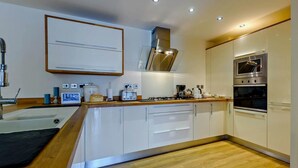 A modern kitchen with white cabinets, a built-in oven, a gas stove, and a microwave. - 2 Bed in Tenby (oc-fb116) (Tenby)