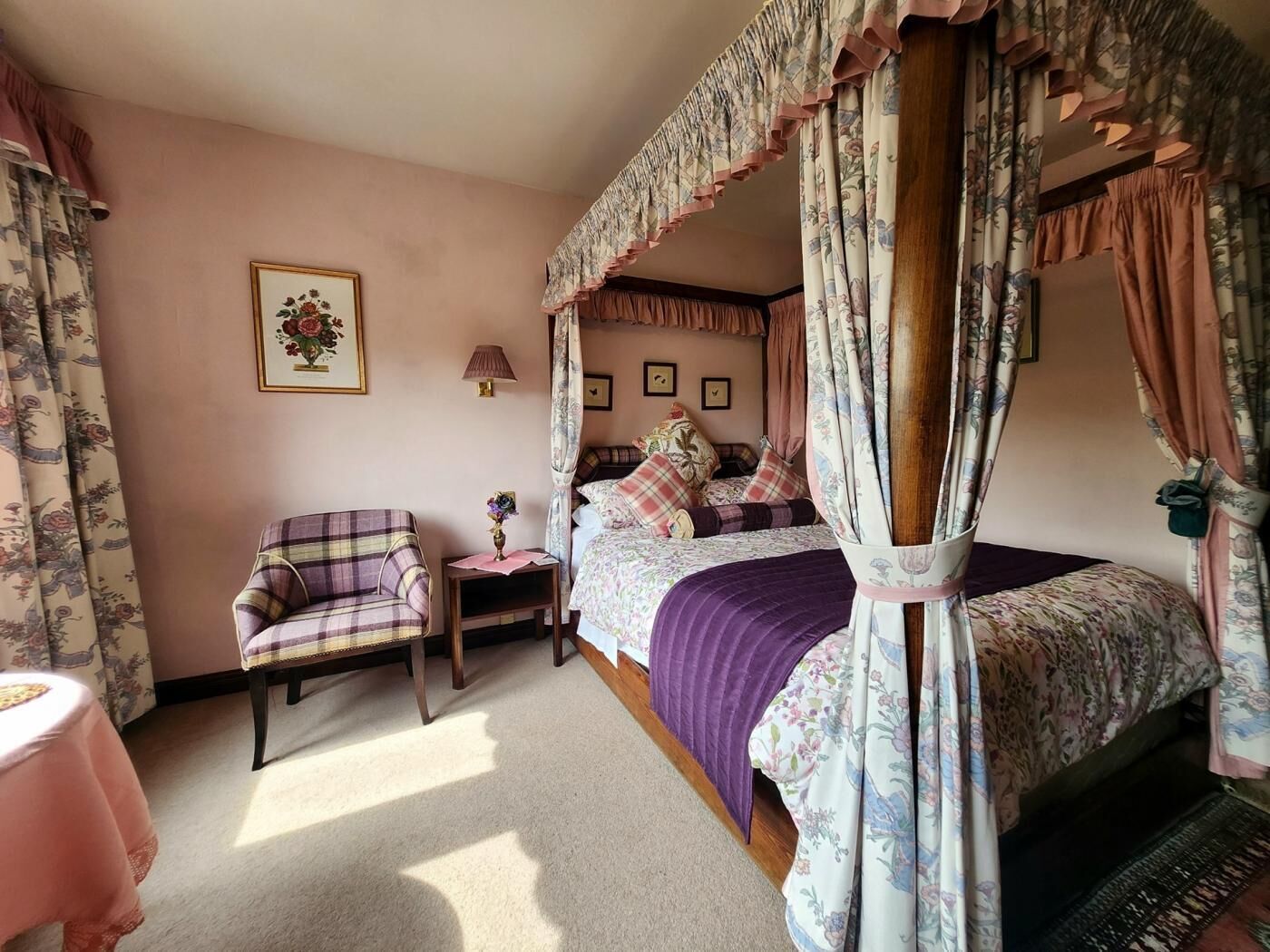 Una camera da letto con un letto a baldacchino, una sedia, un tavolino e una lampada.