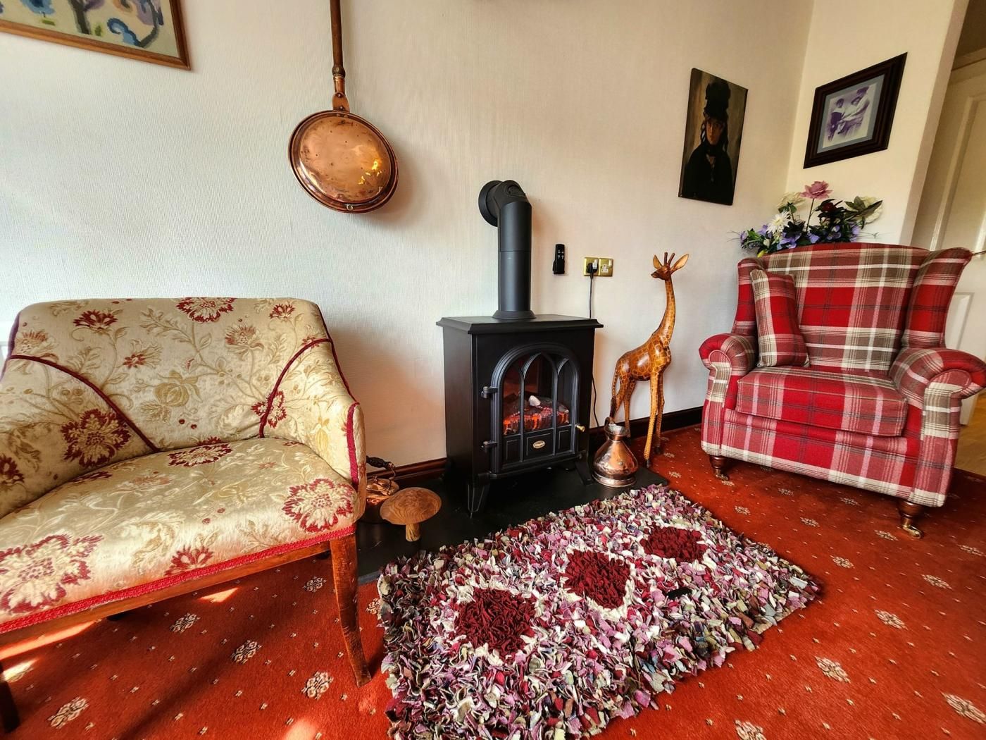 A living room with a sofa, a plaid chair, a fireplace, and a rug.