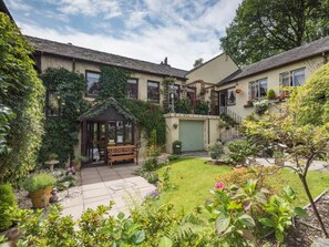 A courtyard with a wooden bench, potted plants, and a small garden area. - 2 Bed in Coniston (oc-sz581) (Coniston)