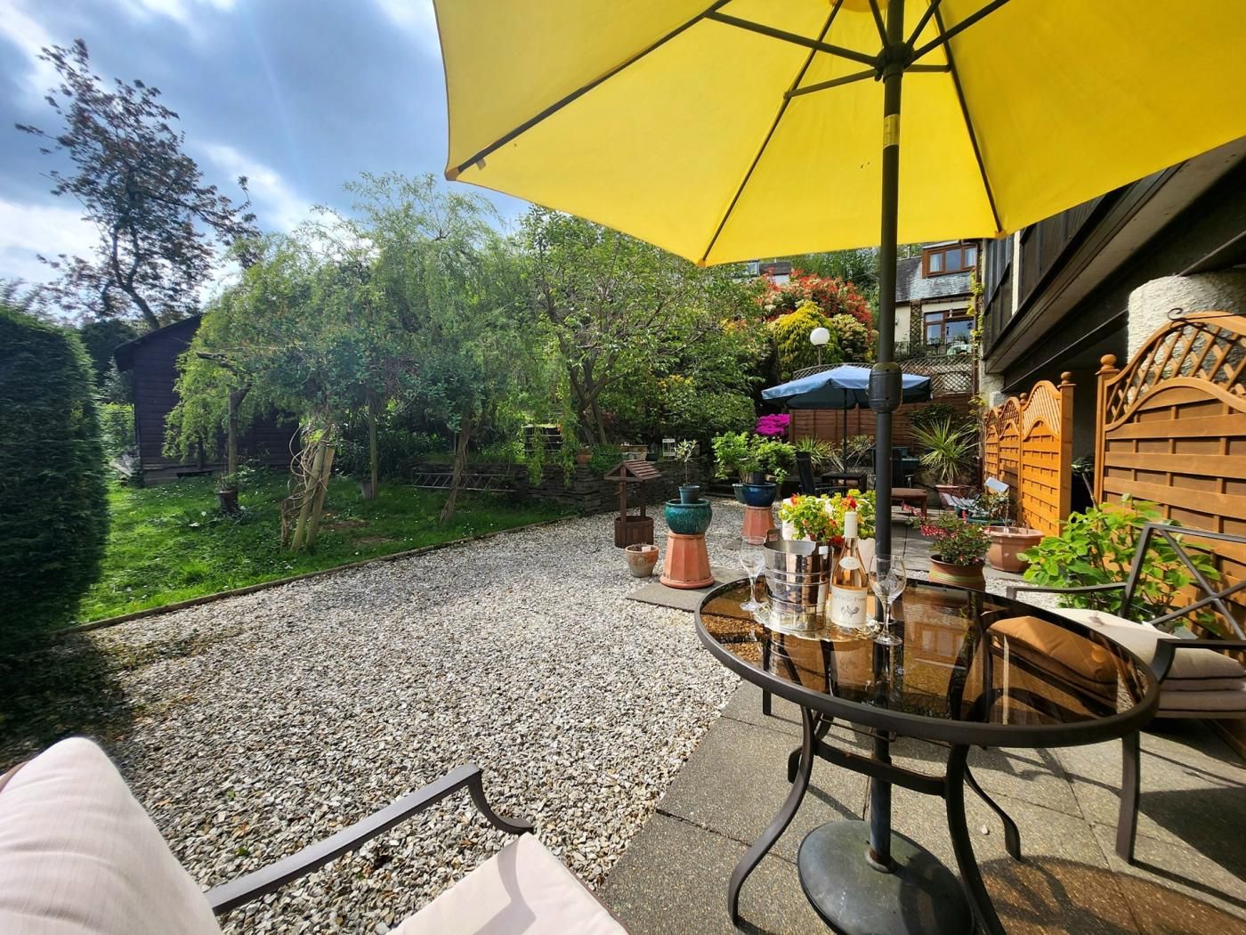 A patio with a round table, chairs, and a yellow umbrella.