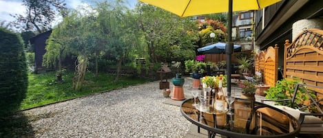 Eine Terrasse mit einem runden Tisch, Stühlen und einem gelben Sonnenschirm.
