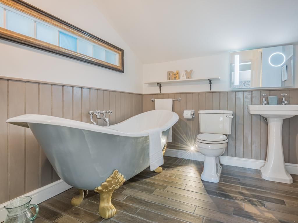 Ein Badezimmer mit Badewanne auf Füßen, Toilette und Waschtisch.