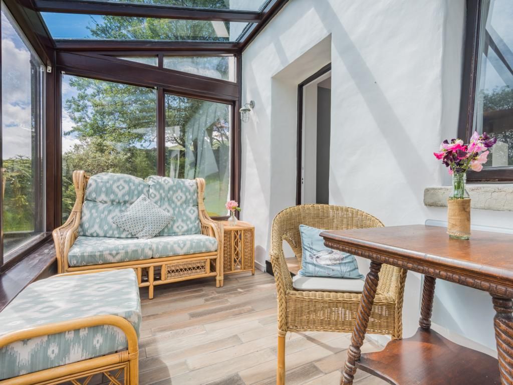 A room with a glass ceiling, wicker furniture, and a wooden table.
