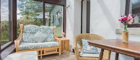 A room with a glass ceiling, wicker furniture, and a wooden table.