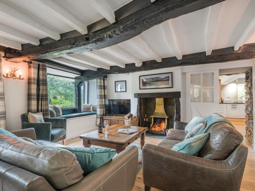 A cozy living room with leather sofas, a fireplace, and a stone fireplace surround.