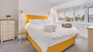Et soveværelse med seng, natbord, lampe og vindue med udsigt.