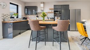 Et moderne køkken med en central ø, barstole og et spisebord med gule stole.