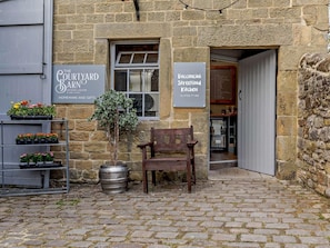A stone building with signs for 'The Courtyard Barn' and 'Boccocini Streetfood Kitchen.' - 3 Bed in Eyam (oc-pk835) (Eyam)