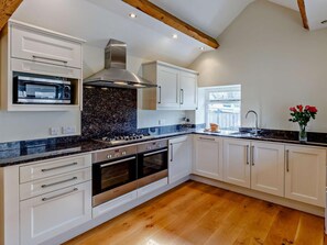 A modern kitchen with white cabinetry, a built-in oven, a stainless steel range hood, and a window providing natural light. - 3 Bed in Eyam (oc-pk835) (Eyam)