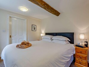 A hotel room with a bed, a nightstand, a lamp, and a door. - 3 Bed in Eyam (oc-pk835) (Eyam)