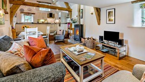 Una sala de estar acogedora con chimenea, televisor y comedor, con una cocina al fondo.