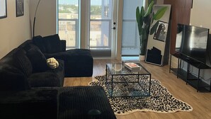 Olohuoneessa on kattotuuletin, musta sohva, lasinen sohvapöytä ja leopardikuvioinen matto.