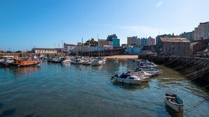 Una marina con imbarcazioni ormeggiate, una spiaggia sabbiosa e edifici sullo sfondo.