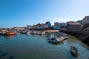 Ein Yachthafen mit vertäuten Booten, ein Sandstrand und Gebäude im Hintergrund.