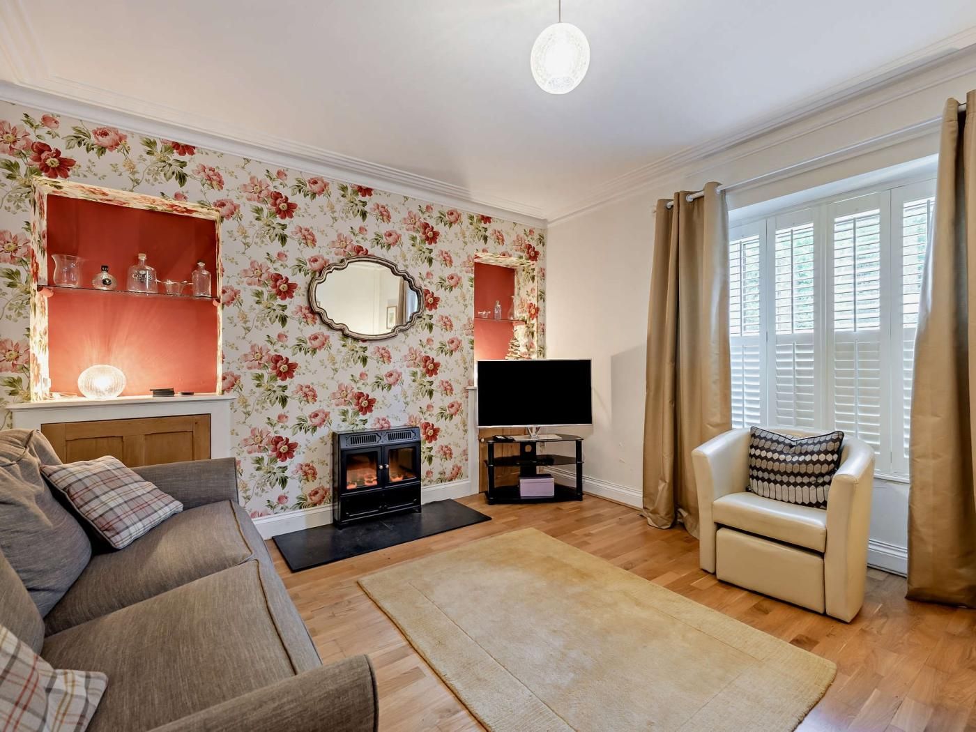 A living room with a sofa, a television, a fireplace, and a large window with curtains.