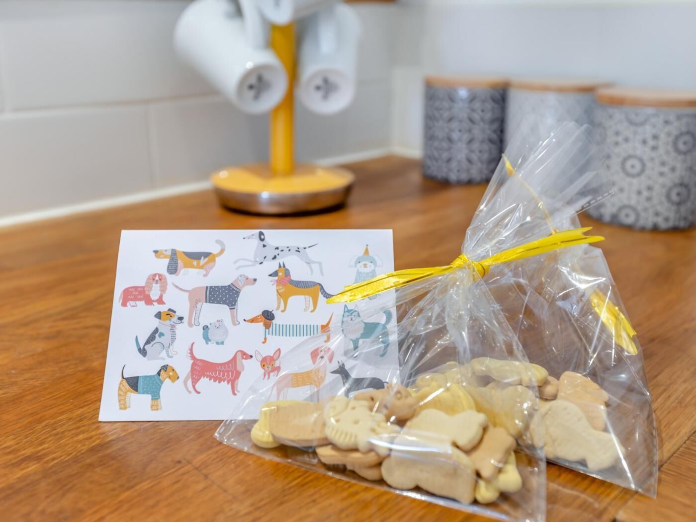 Un comptoir de cuisine avec un sac en plastique rempli de biscuits et une carte illustrée de chiens.