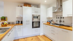 Une cuisine moderne avec des meubles blancs, une hotte en acier inoxydable et un plan de travail en bois.