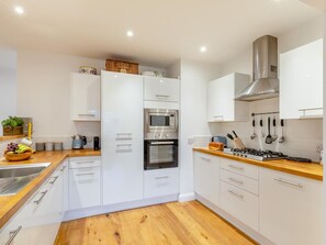A modern kitchen with white cabinetry, a stainless steel range hood, and a wooden countertop. - 2 Bed in Brixham (oc-73625) (Brixham)