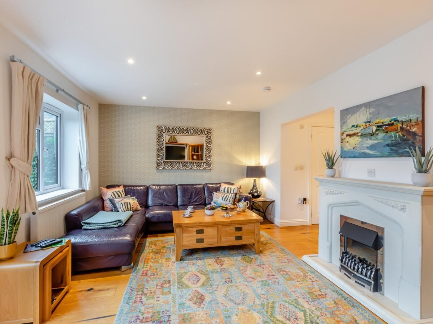 A living room with a sofa, coffee table, fireplace, and a painting on the wall.