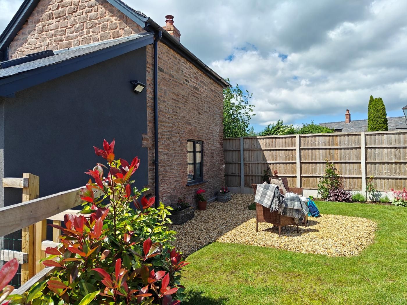 A residential property with a stone facade, a wooden deck, and a fenced backyard.