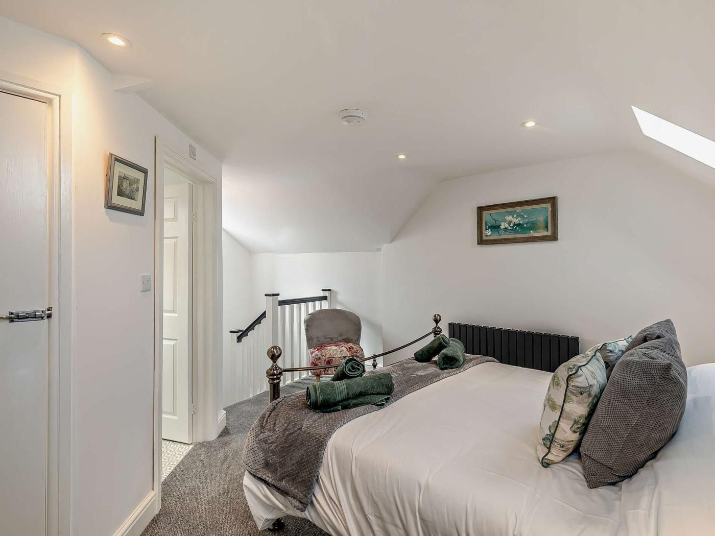 Een slaapkamer met een bed, een stoel, een radiator en een trap.