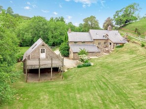 A large, multi-story stone house with a wooden deck and a stone chimney.