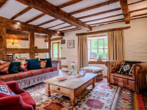 A rustic interior with exposed wooden beams, a patterned rug, and a traditional sofa.