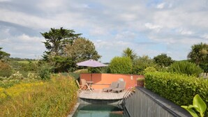 A swimming pool with a wooden deck, lounge chairs, and a table with an umbrella. - 4 Bed in Wembury (oc-54383) (Wembury)